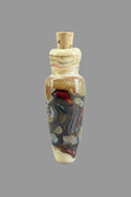 A small decorative glass bottle pendant with a cork cap, featuring multicolored swirls of red, blue, and purple inside a translucent amber-colored glass body, resting on a black textured background.