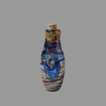A small handcrafted glass bottle with a cork stopper, featuring a marbled pattern of blue, purple, brown, and yellow, set on a wooden surface.