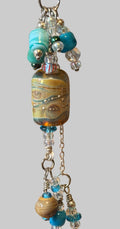 A close-up of a handmade beaded keychain or keyring charm with a large marbled lampwork bead, turquoise and blue beads, clear glass beads, and silver-toned chains.