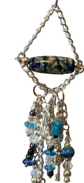 A close-up of a beaded jewelry display featuring a silver-toned chain with a marbled dark bead, multiple dangling charm strands in blue, clear, and silver.