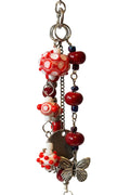 A handmade beaded keychain or charm with red and white patterned glass beads, dark red beads, silver-tone metal rings, and a butterfly charm. 
