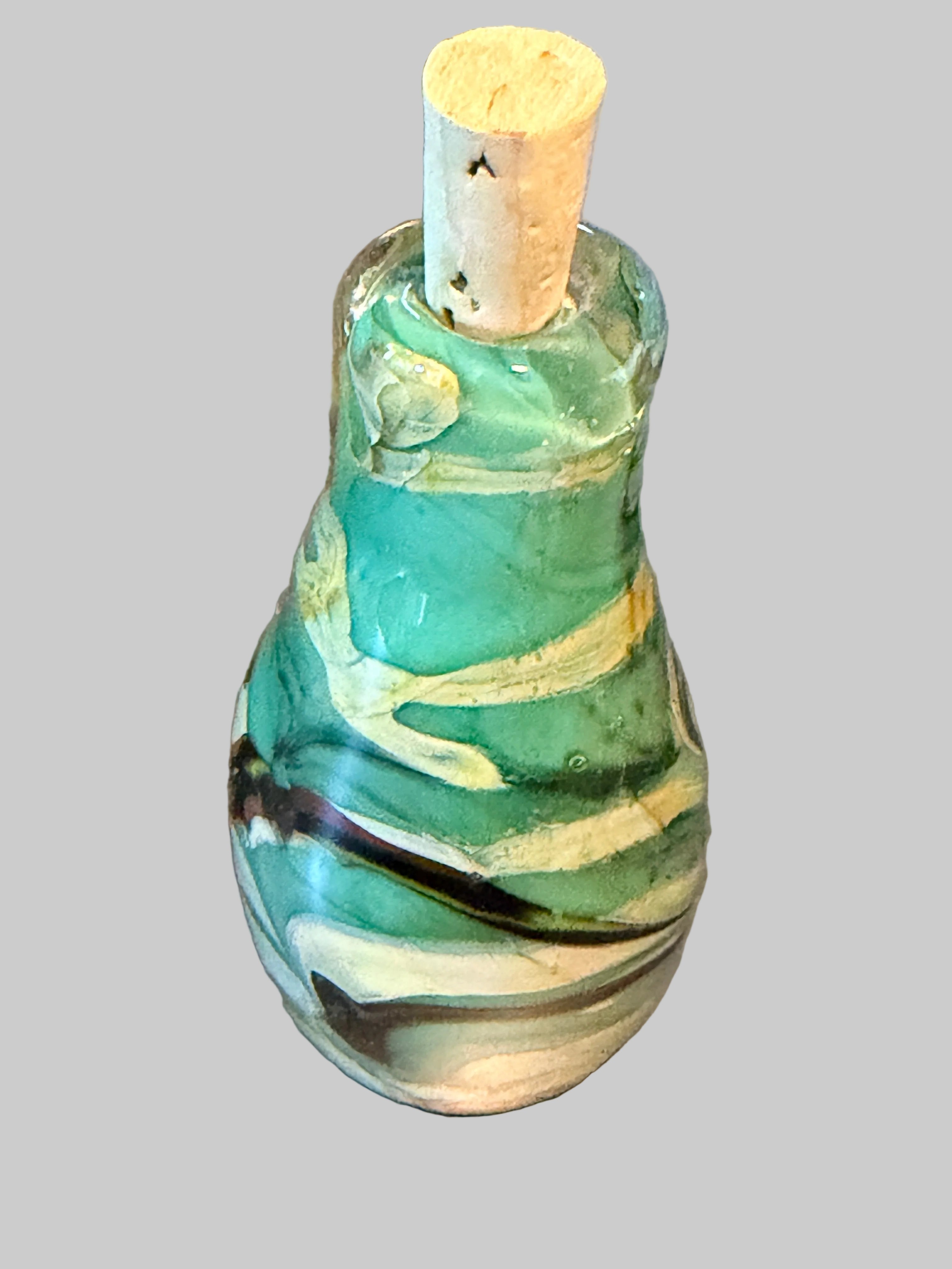 A small glass bottle with a cork stopper, featuring a marbled pattern of green, white, and black swirls.