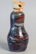 A small decorative bottle with a cork stopper, featuring a marbled pattern of brown, gray, and red glass. 